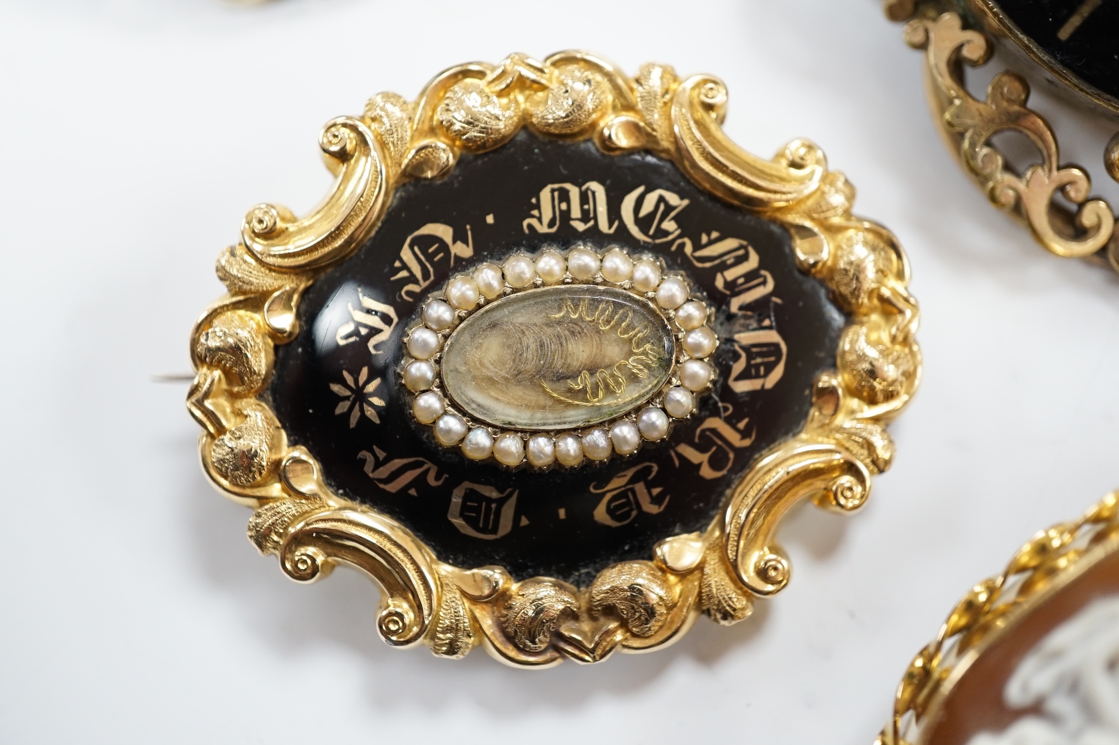 Three assorted Victorian mourning brooches, including two yellow metal, one set with seed pearls and diamond chip and inscribed and dated 1847, 48mm and two cameo shell set brooches.